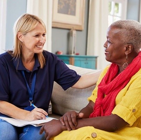 A woman is sitting on a couch talking to an older woman.