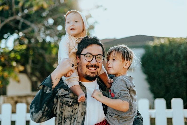 A man is carrying two children on his shoulders.