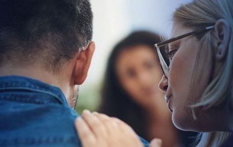 A woman is kissing a man on the cheek in front of a group of people.