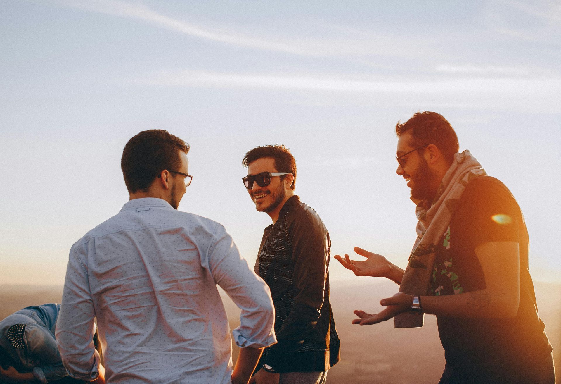 Three men are standing on top of a mountain talking to each other.