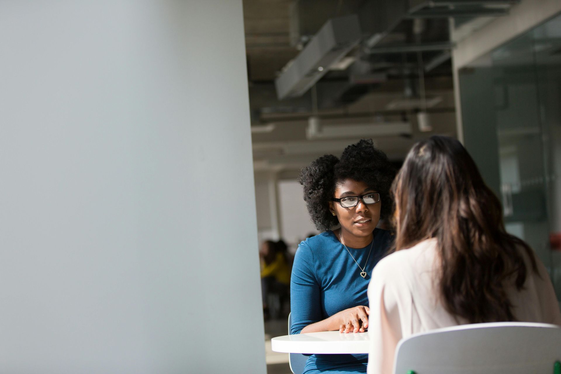 Two women are sitting at a table having a conversation.