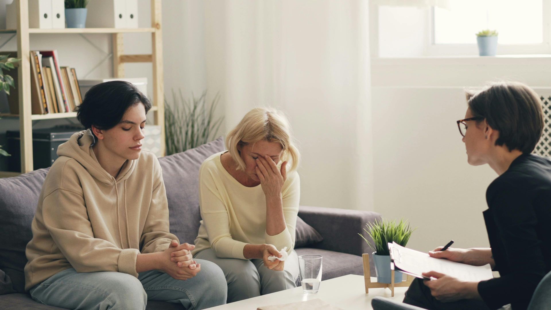 A man and a woman are sitting on a couch talking to a woman.