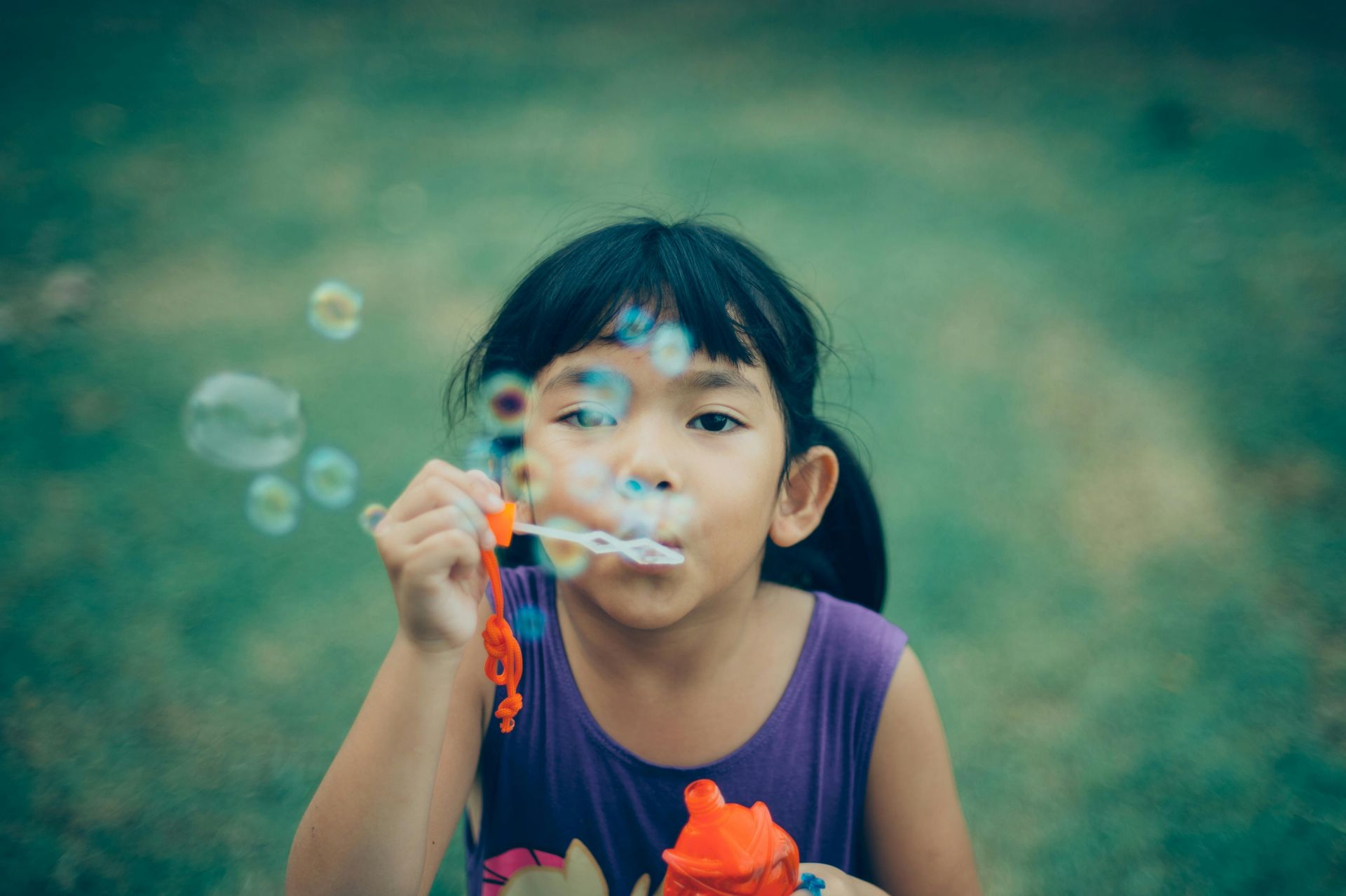 A little girl is blowing soap bubbles in the park.