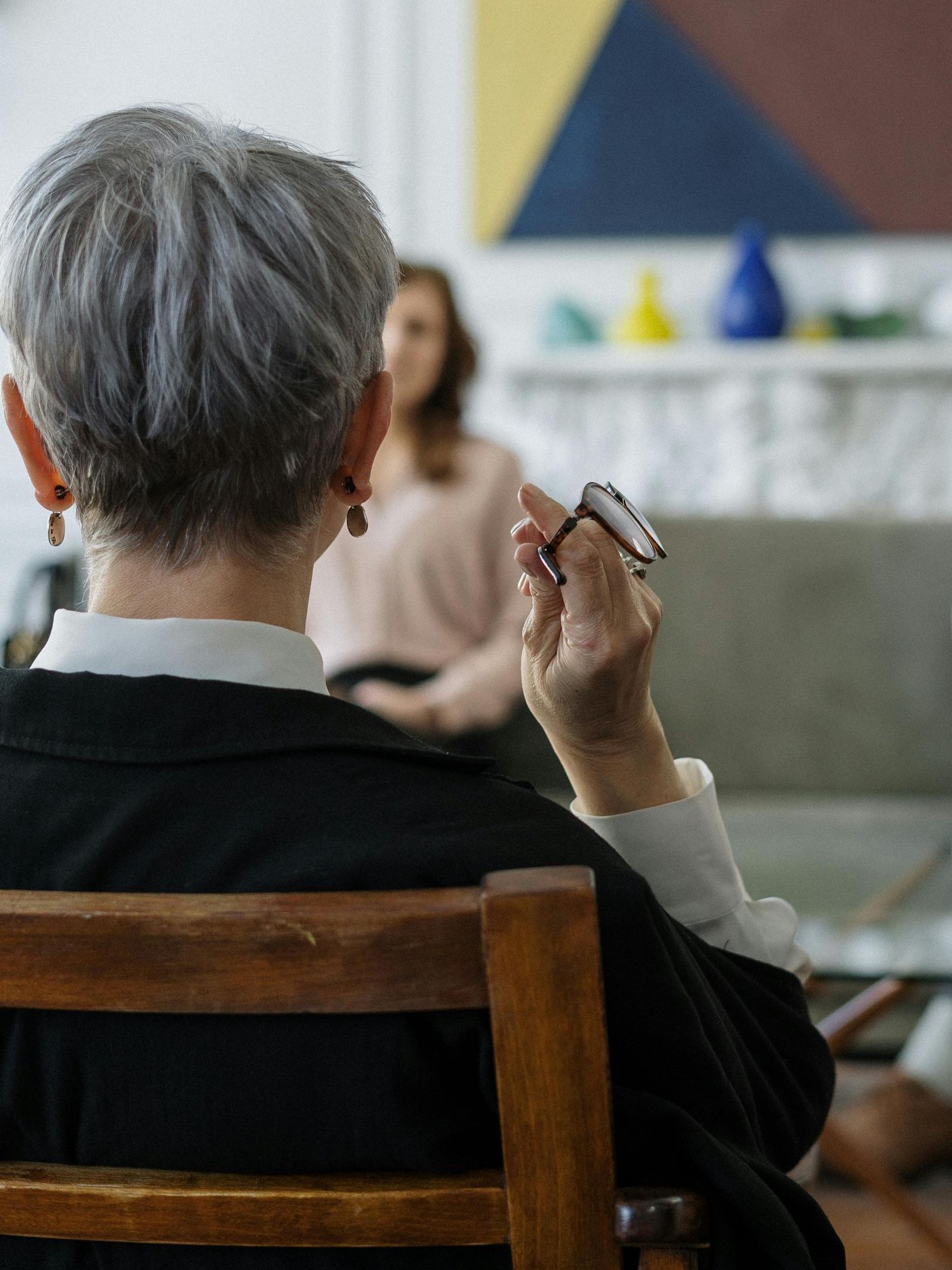 A woman is sitting in a chair talking to a group of people.