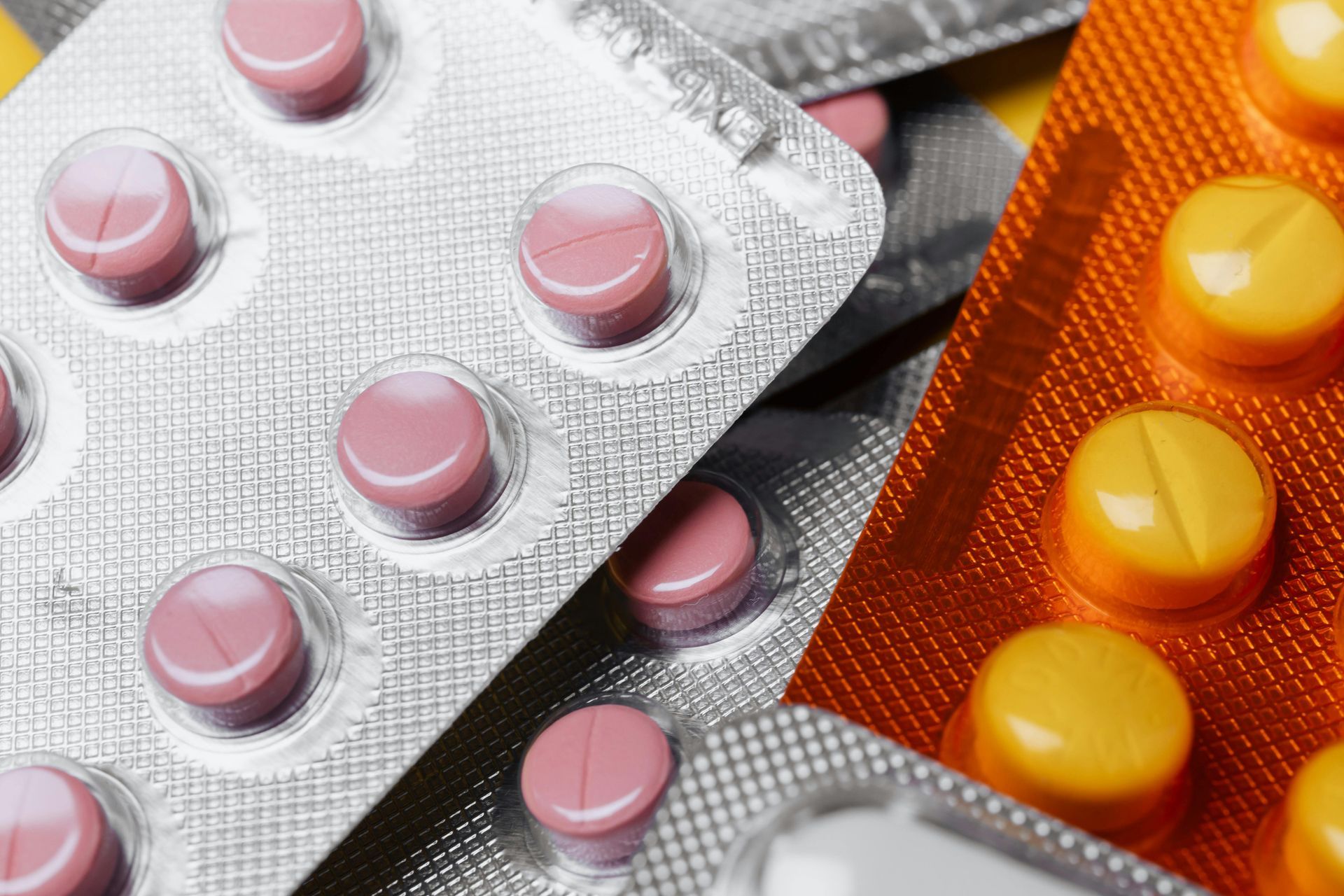 Close-up of blister packs with pink and yellow pills.