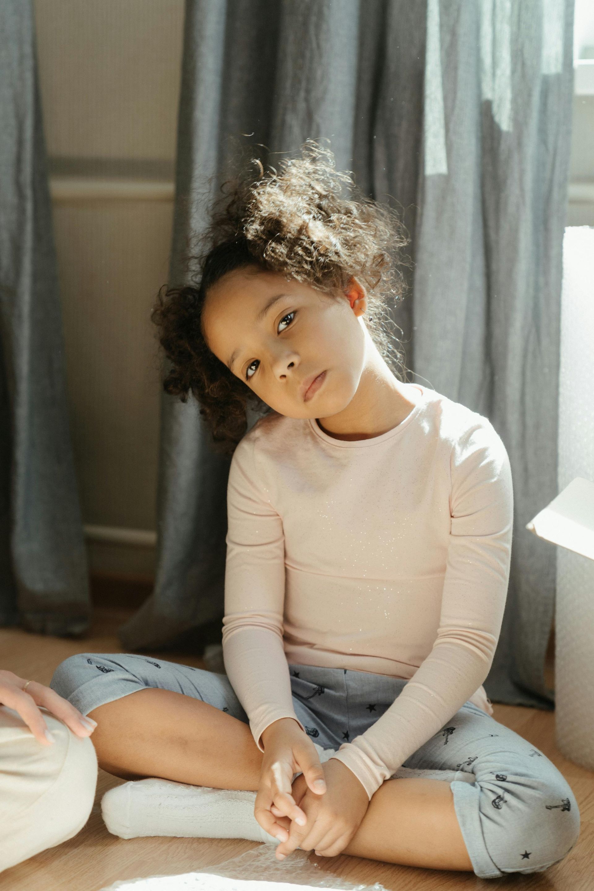 A little girl sits cross legged on the floor.