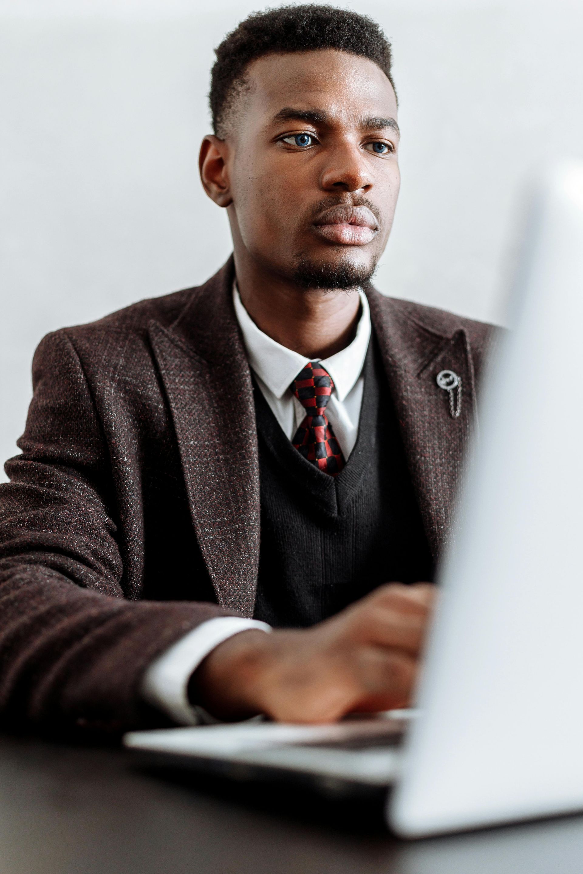 Man in suit jacket and tie working on a laptop, indoors.