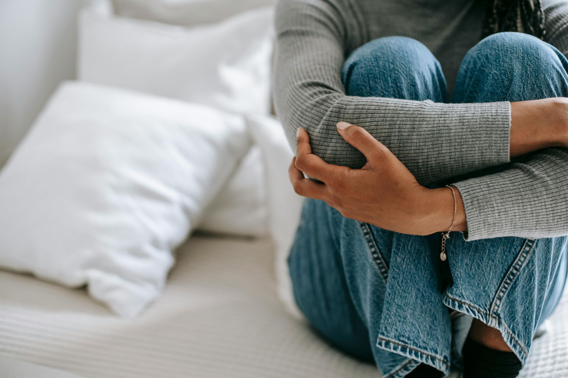 A woman is sitting on a bed with her legs crossed.