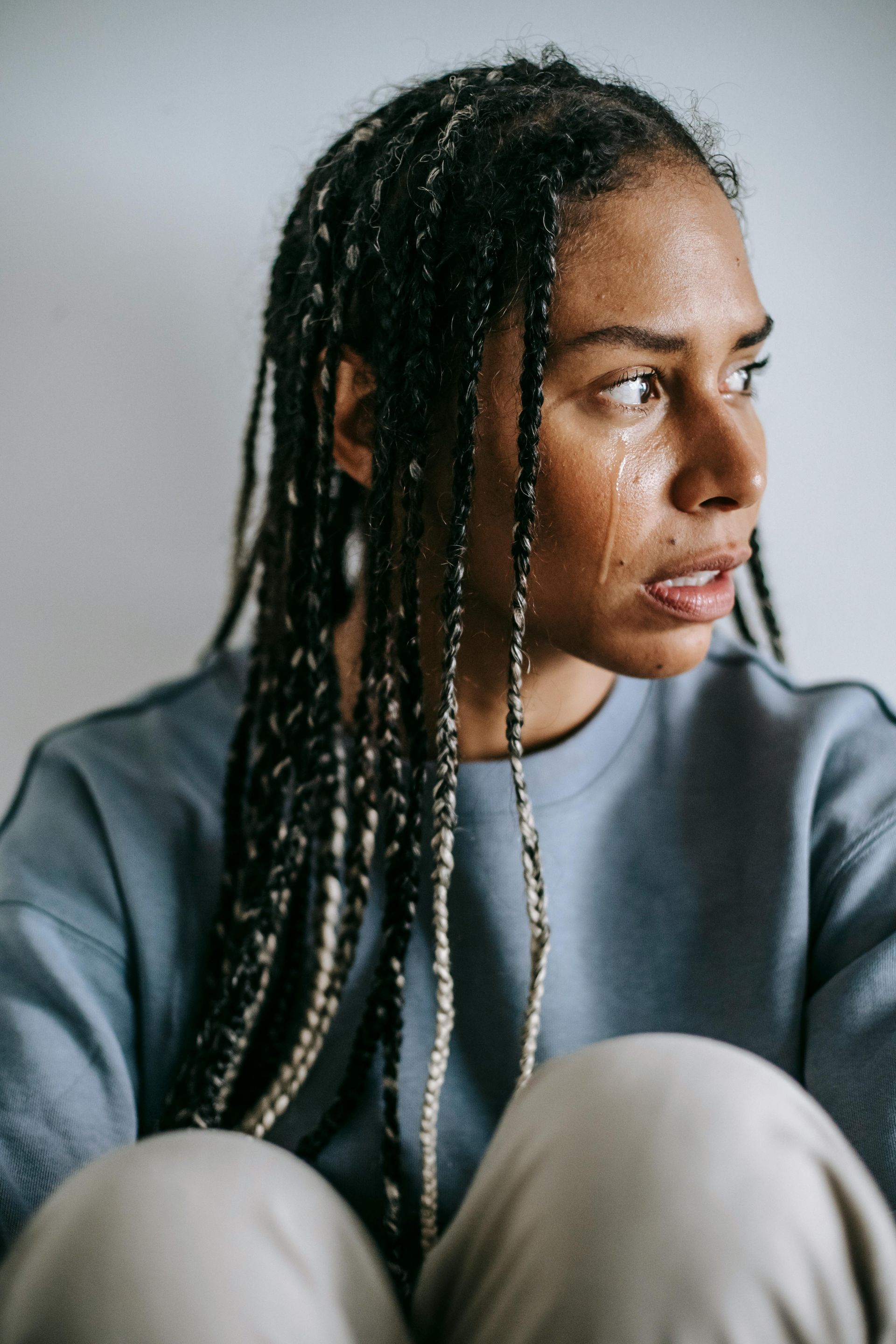 A woman with braids is crying while sitting down.