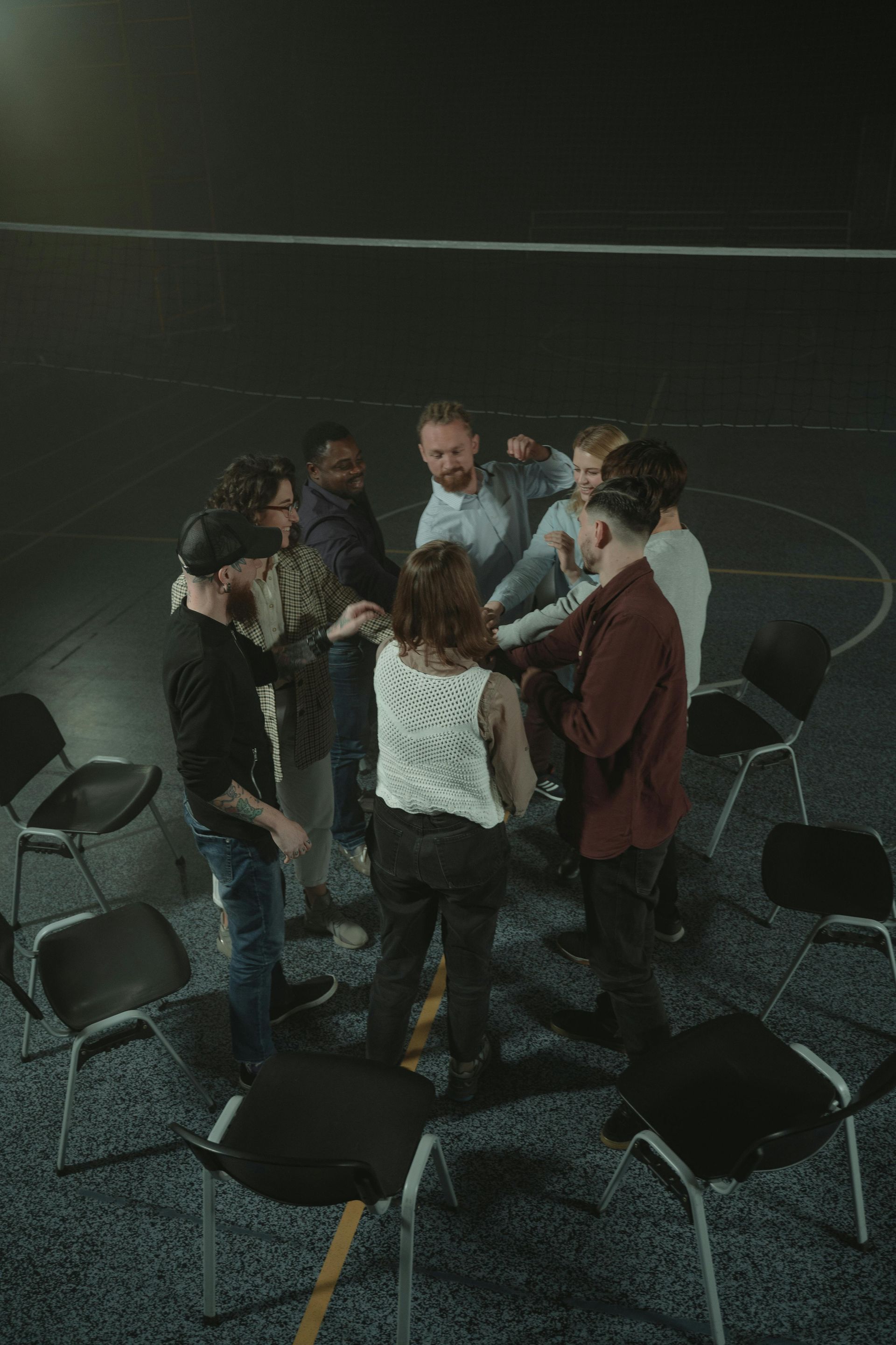 A group of people are standing in a circle in a dark room.