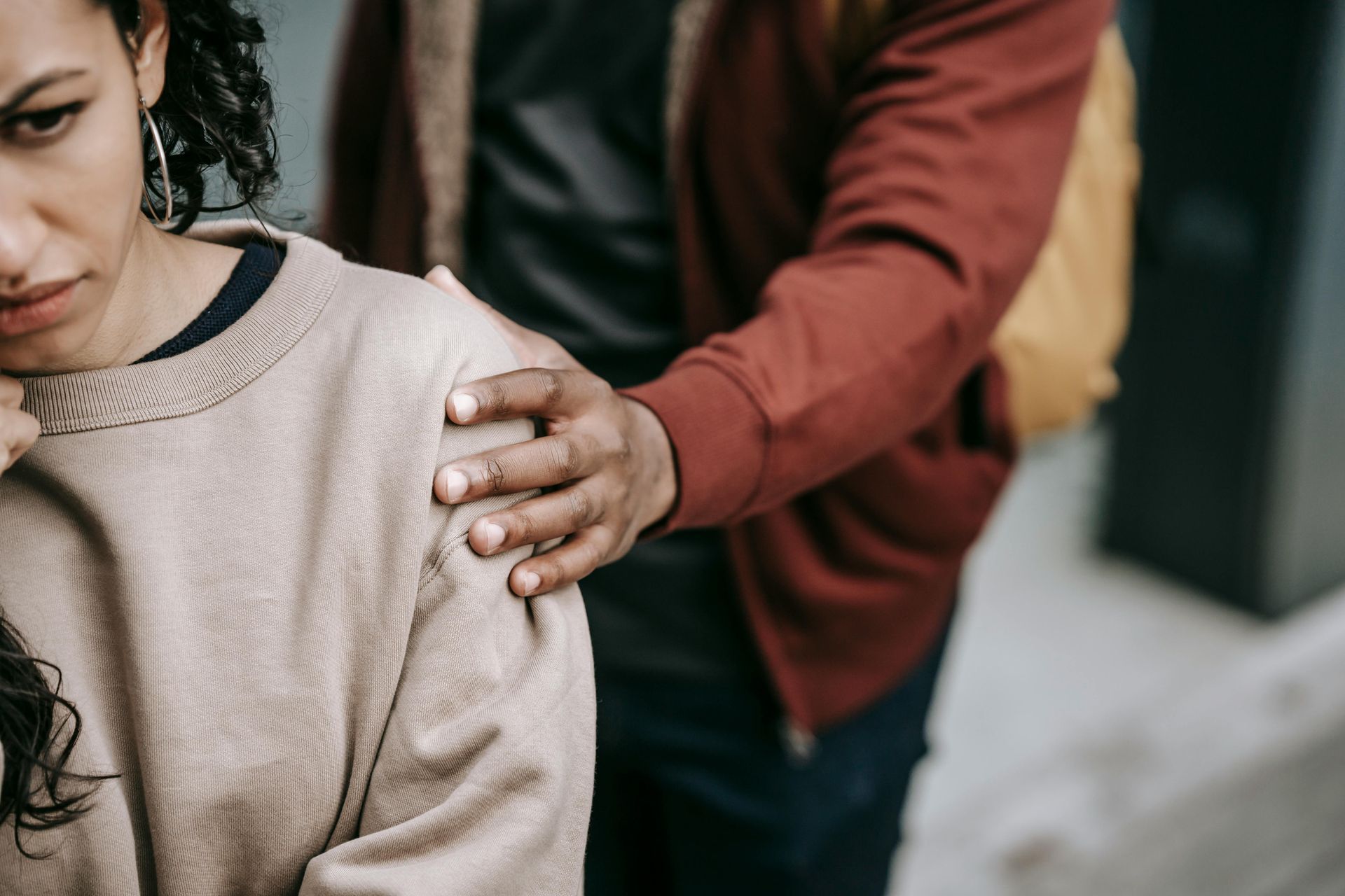 A man is putting his hand on a woman 's shoulder.