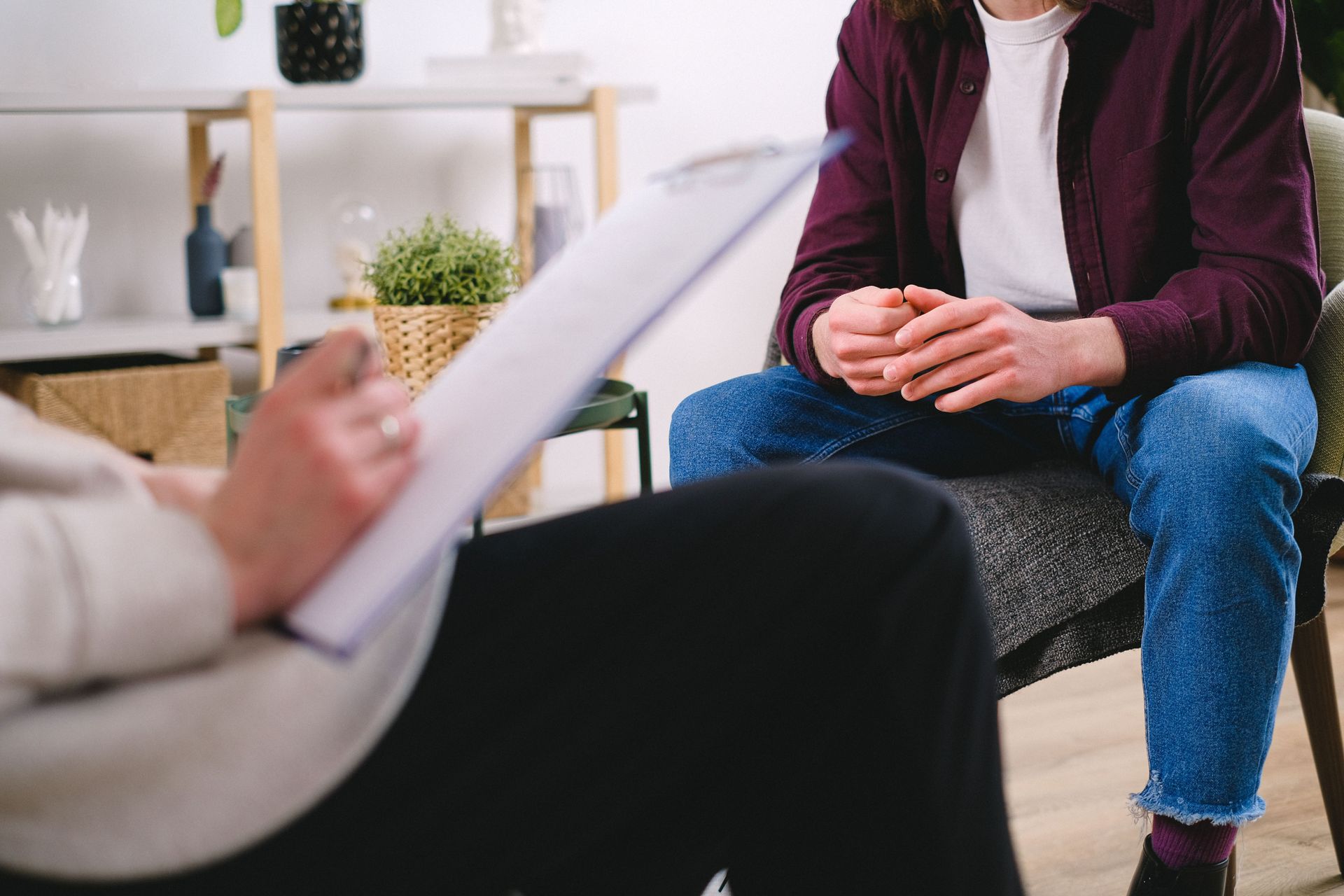 Counselor and client seated in a therapy office, with a clipboard in the foreground