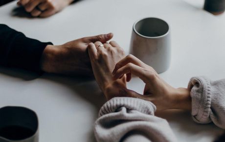 A man and a woman are holding hands at a table.