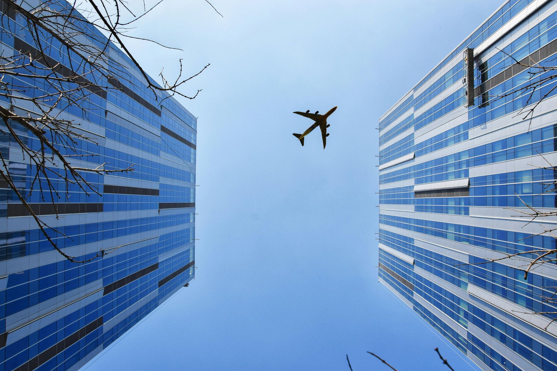An airplane is flying between two tall buildings.