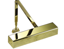 A close up of a brass door closer on a white background