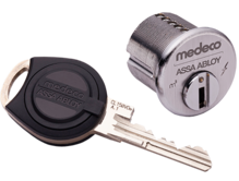 A medeco assa abloy lock and a key on a white background