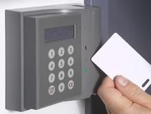 A person is holding a card in front of a keypad.