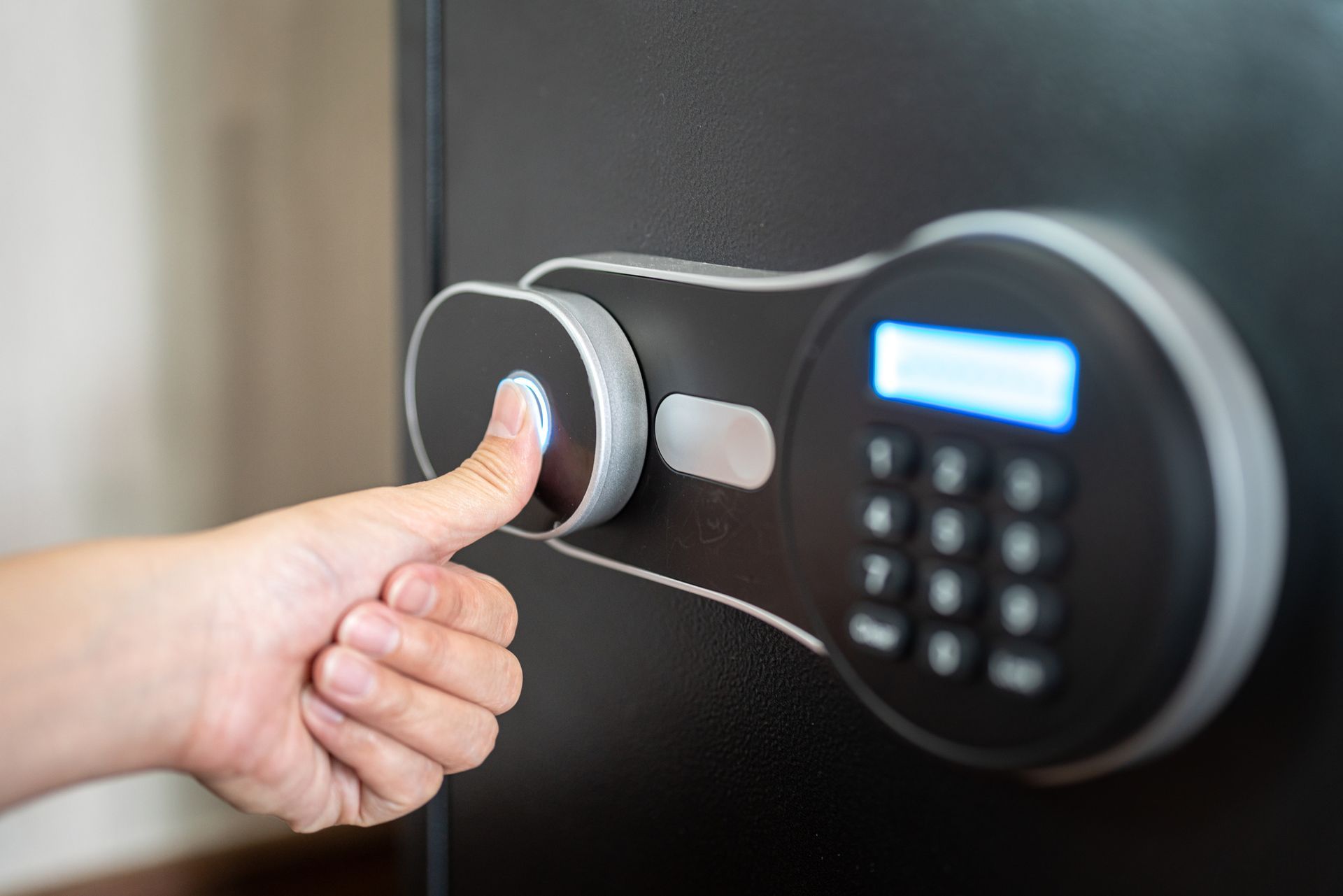 A person is pressing a button on a safe with their finger.