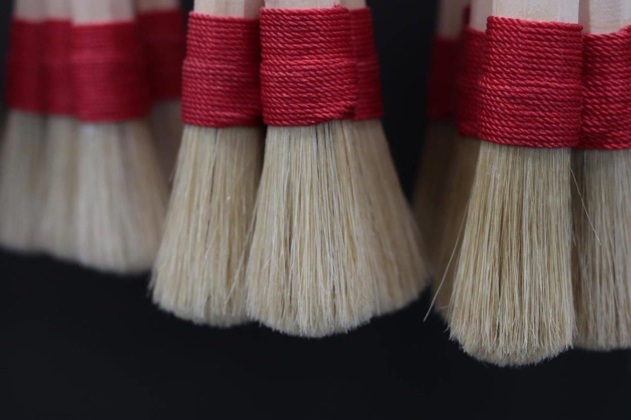 Un primo piano di un mazzo di pennelli con nastri rossi.