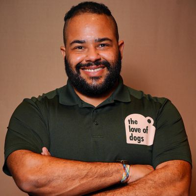 Man with a beard and arms crossed, wearing a green polo shirt with 