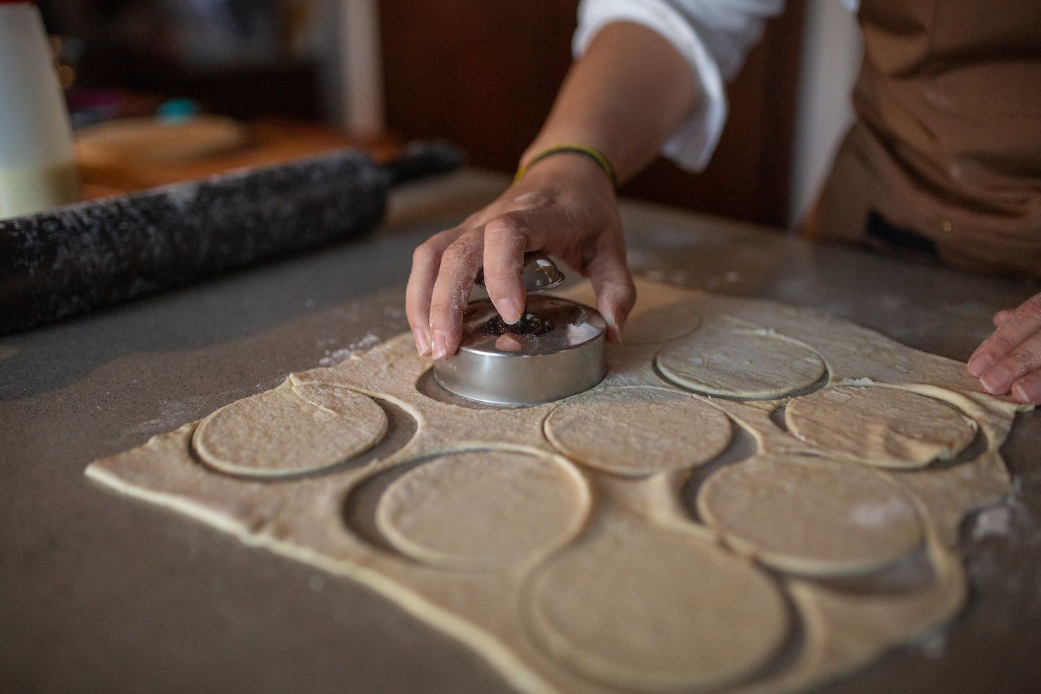 A person is cutting dough into circles with a cookie cutter.