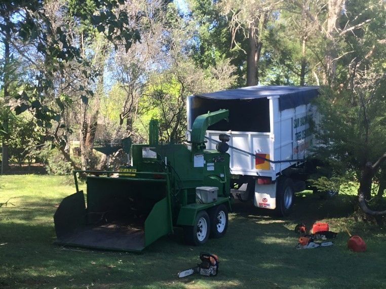 A Tree Chipper is Parked Next to a Trailer in a Park — Sam Backhouse Tree Services in Moss Vale, NSW