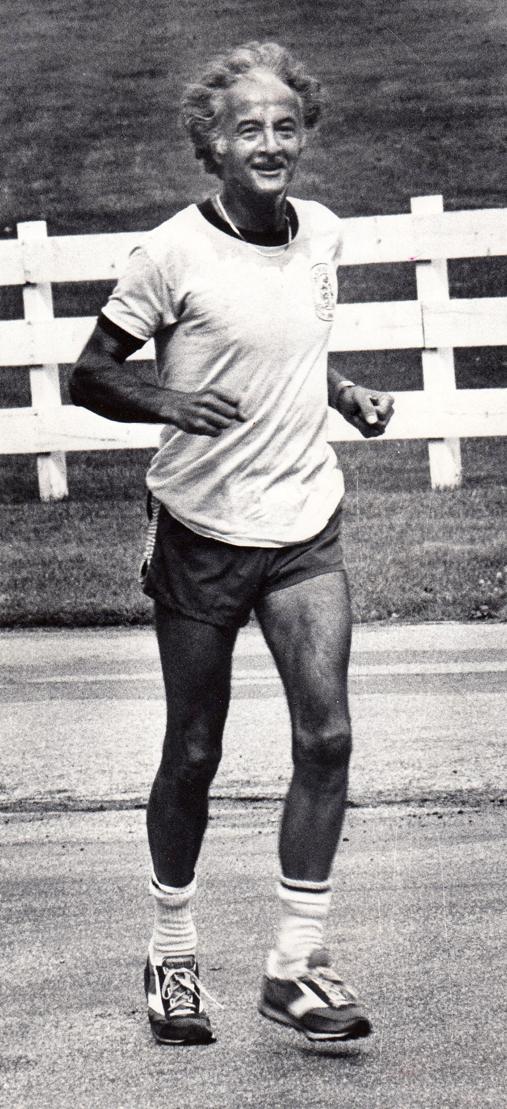 An older person running in shorts and a t-shirt on a path.