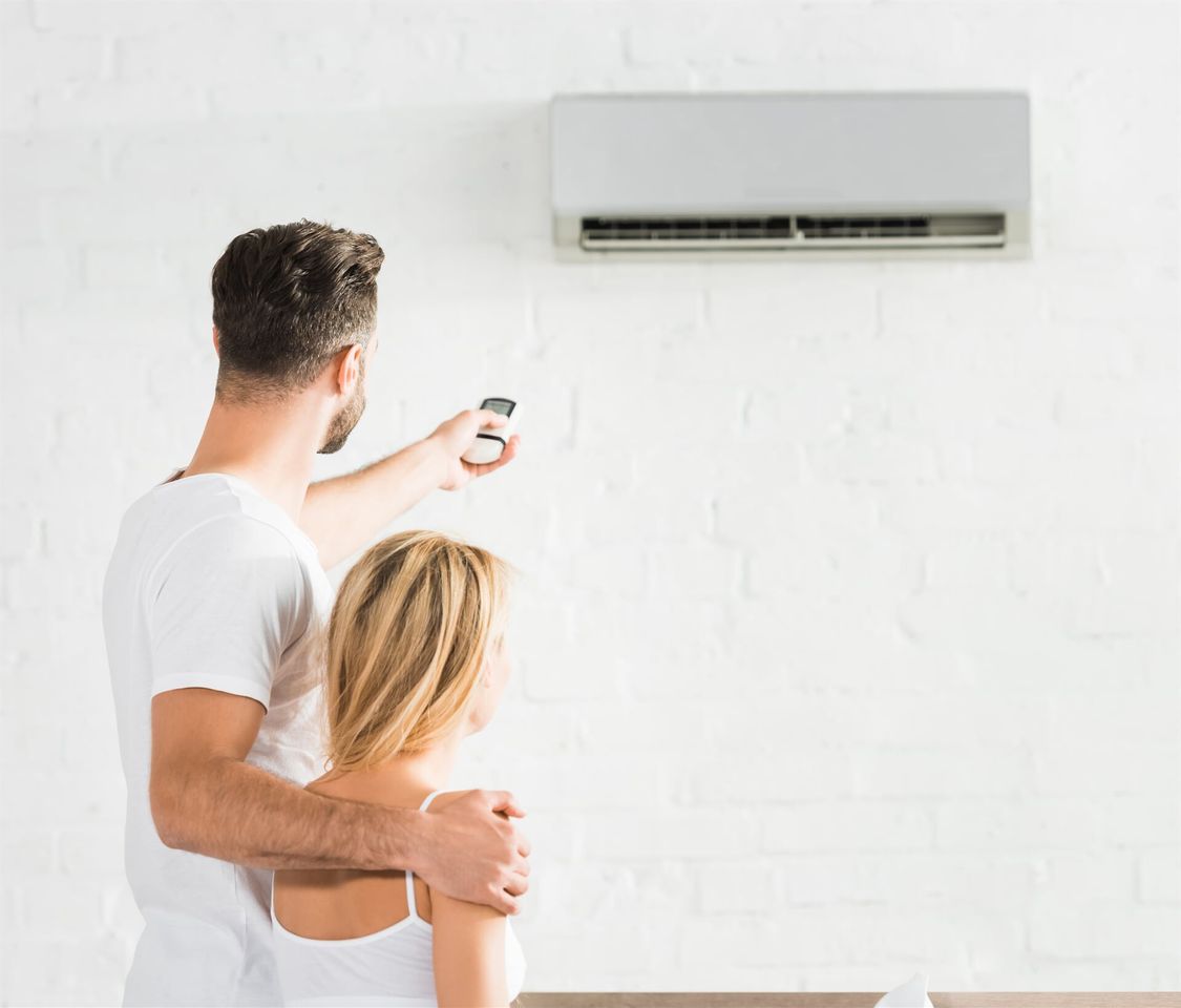 A Couple Turning on Their Air Conditioner — Mick’s Air-Conditioning Services in Gracemere, QLD