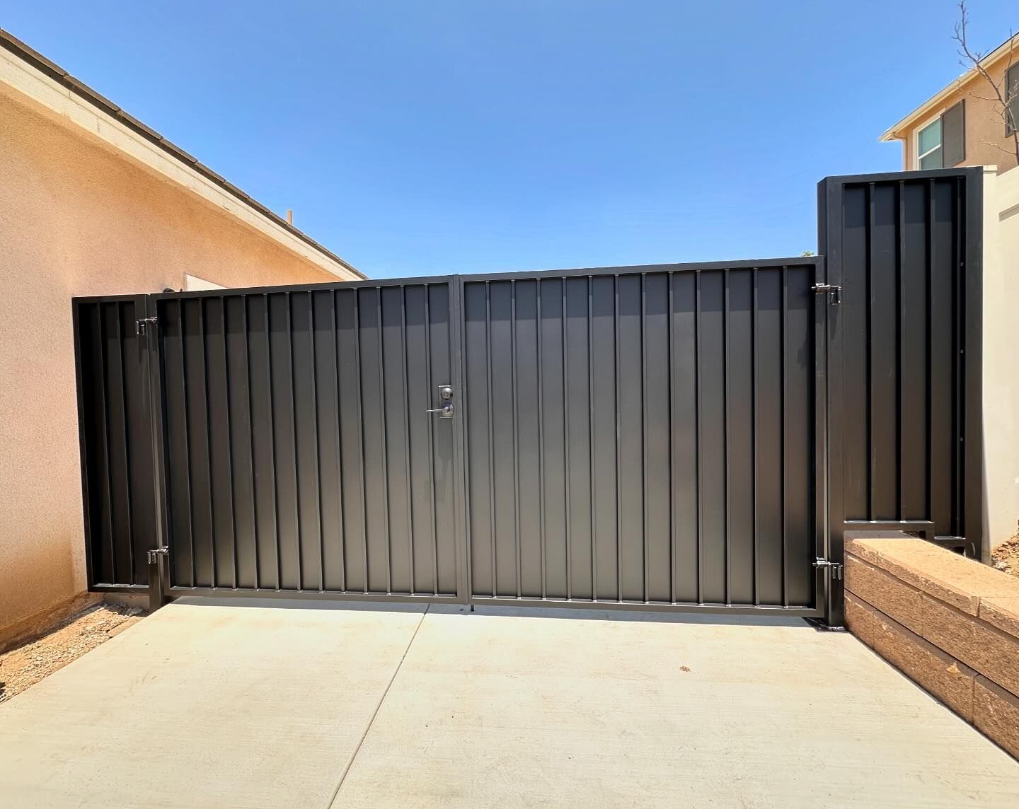 A black gate is sitting on a concrete driveway in front of a house.