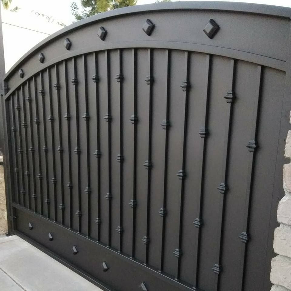 A black fence with a brick wall behind it