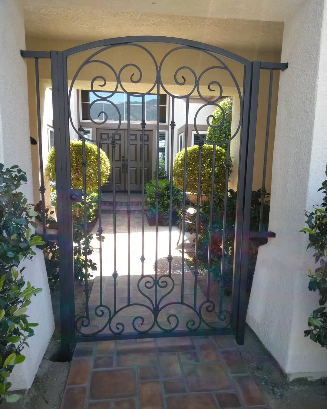A wrought iron gate leading to a house