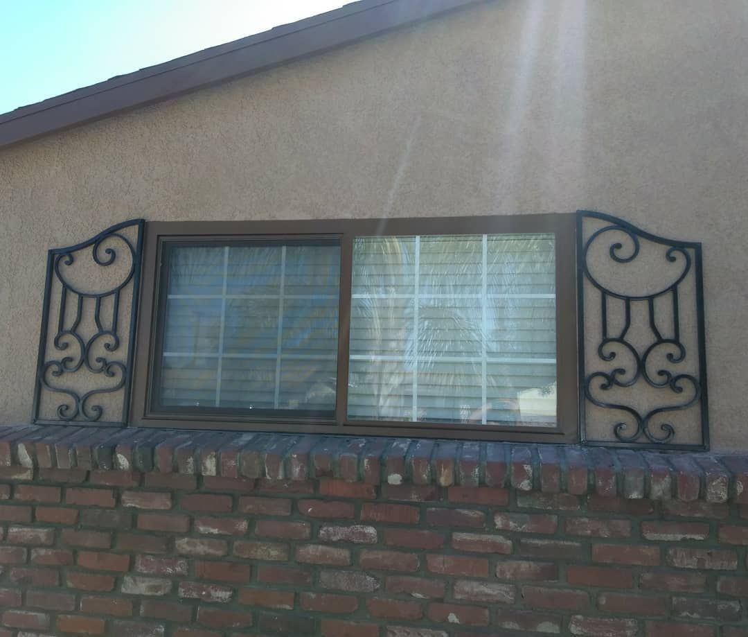 A brick wall with a window with a wrought iron design on it