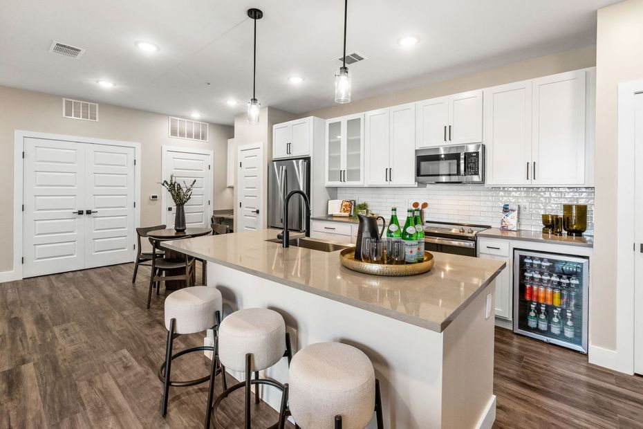 Modern kitchen with white cabinets, island with stools, and built-in refrigerator.