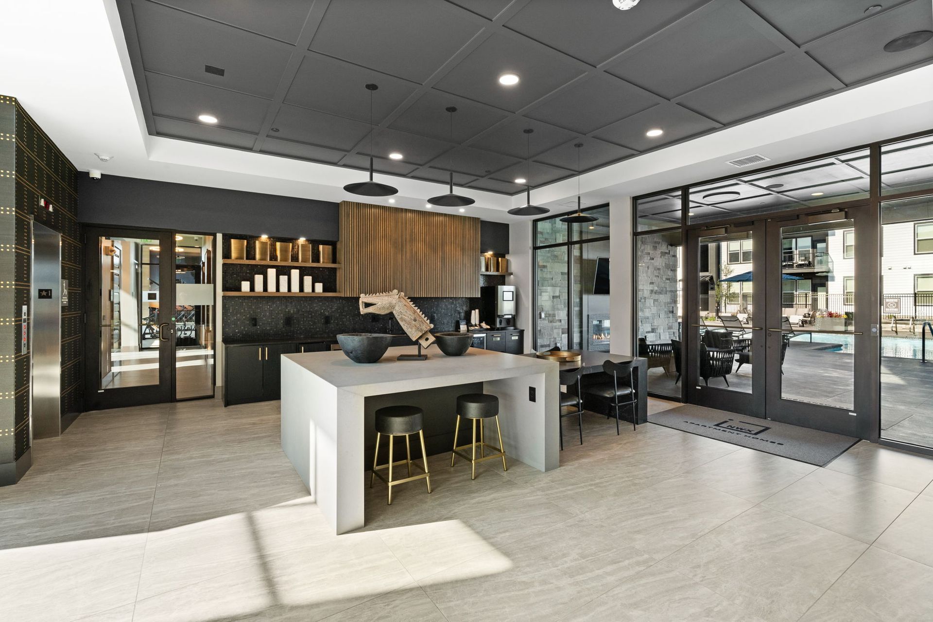 Modern communal kitchen with island, seating, and access to an outdoor patio.