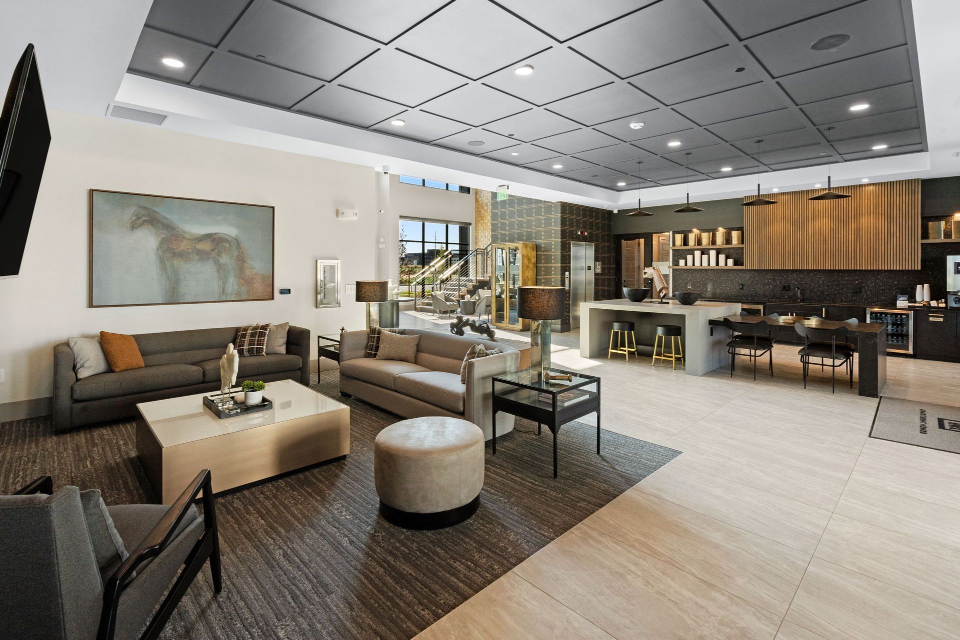 Spacious modern lounge area with couches, coffee table, kitchen island, and dining table under a grid ceiling.