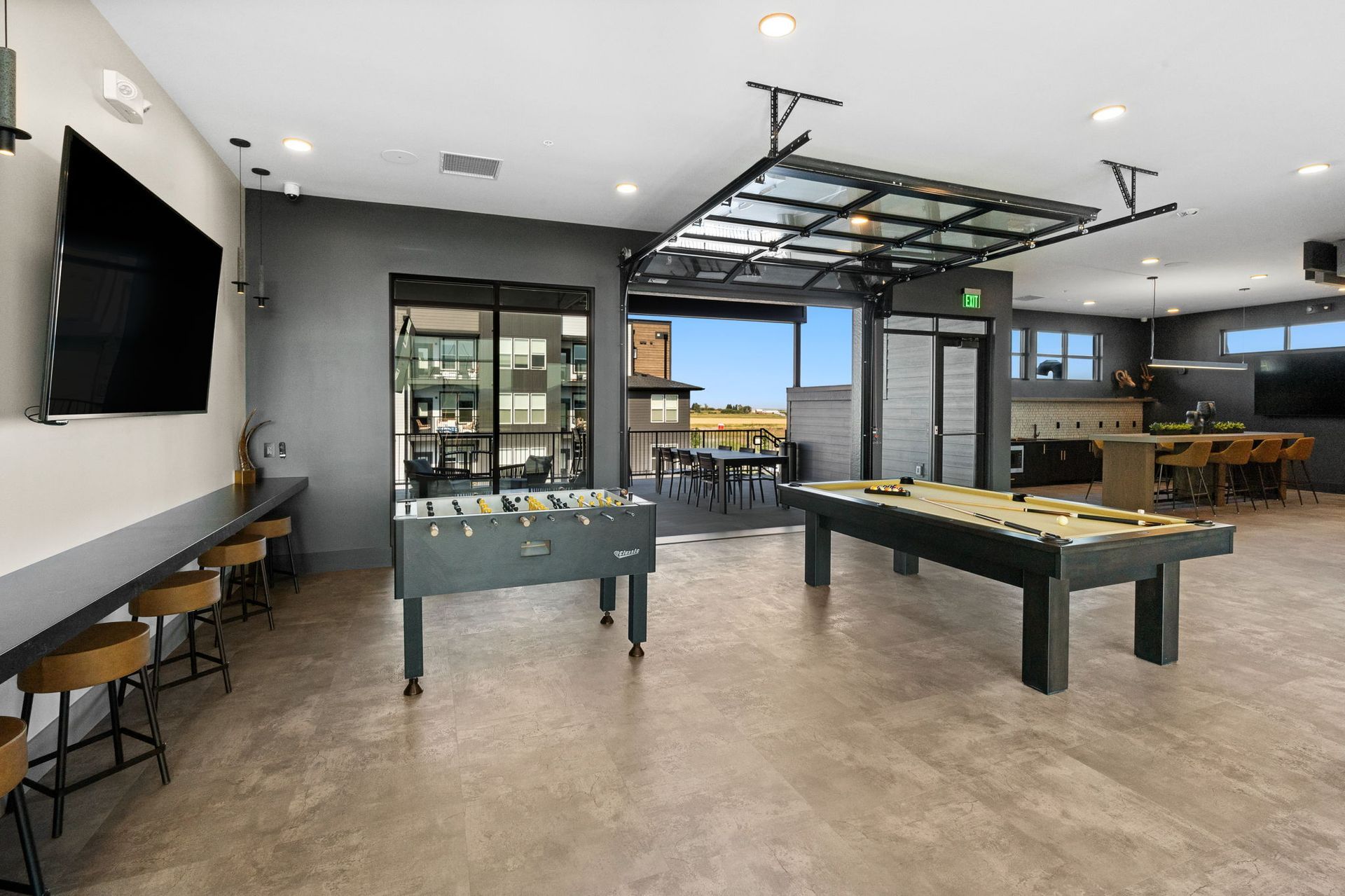 Game room with foosball and pool tables. Open to outdoor patio with seating.