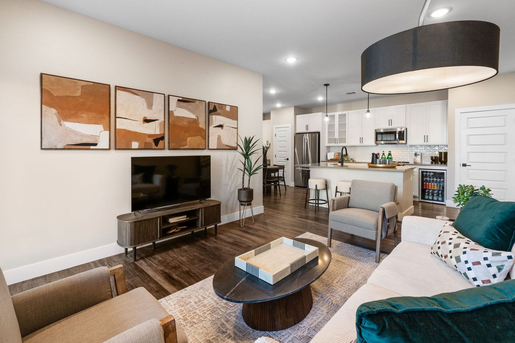 Living room with TV, art, open kitchen, and modern furniture.