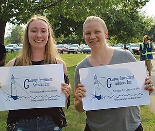 Two women are holding up signs for gasway investment advisors inc.