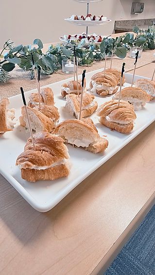 A white plate topped with sandwiches on toothpicks on a wooden table.