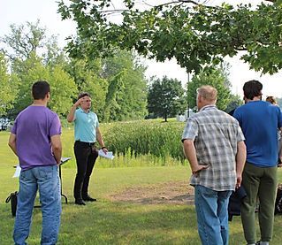 A group of men are standing in a grassy field with trees in the background.