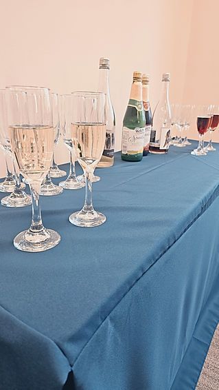 A table with a blue tablecloth and wine glasses and bottles on it.