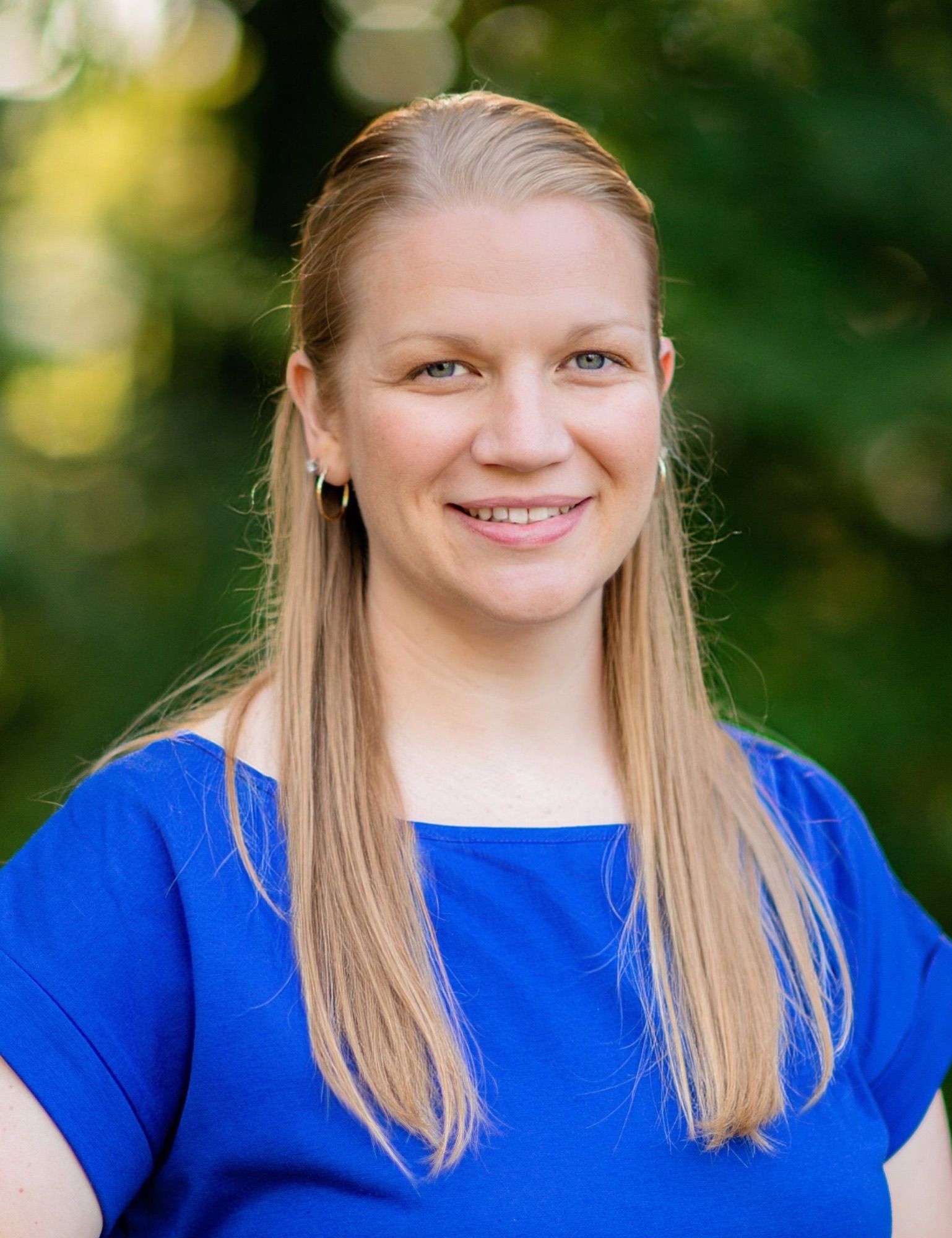 A woman in a blue shirt is smiling for the camera.