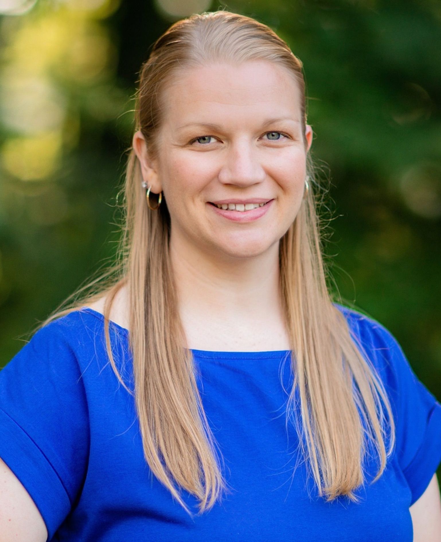 A woman in a blue shirt is smiling for the camera.