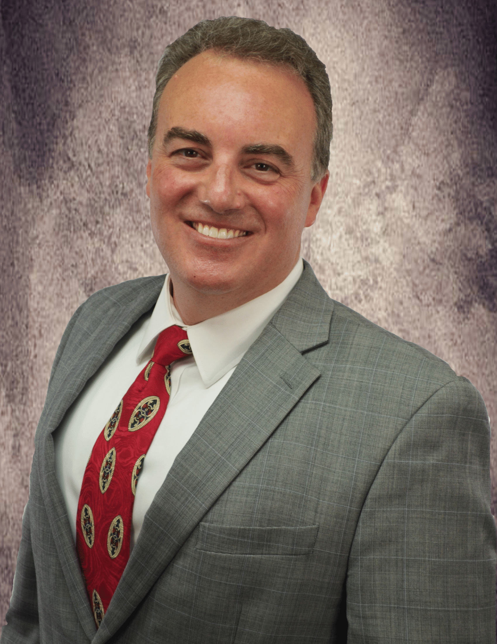 A man in a suit and tie is smiling for the camera