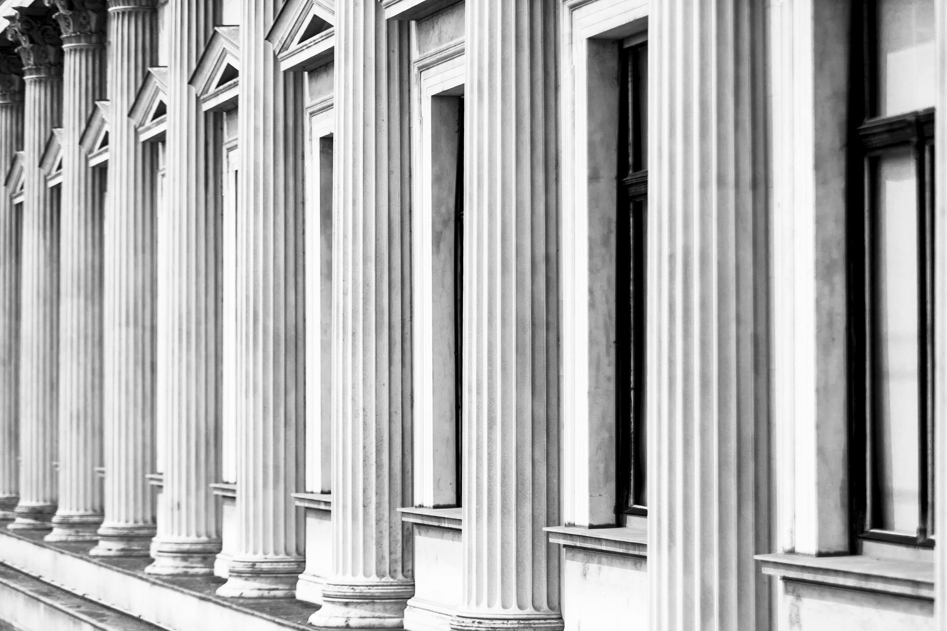 A black and white photo of a row of columns and windows on a building.