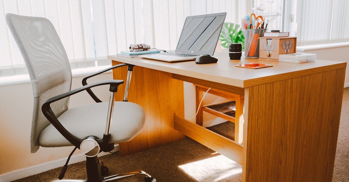 A wooden desk with a chair and a laptop on it.