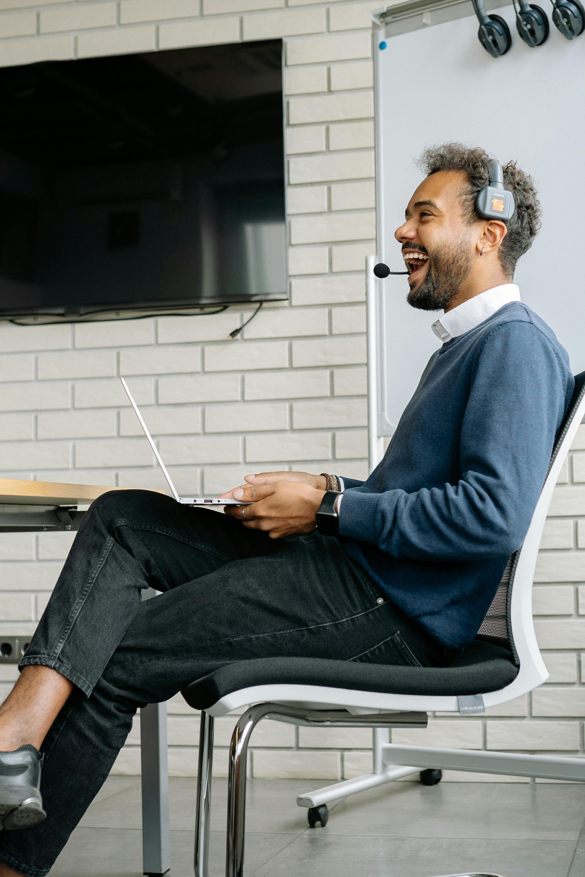 A man is sitting in a chair with his legs crossed while using a laptop computer.