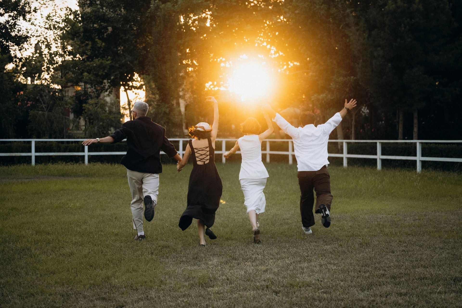 A group of people are running in a field with their arms outstretched.