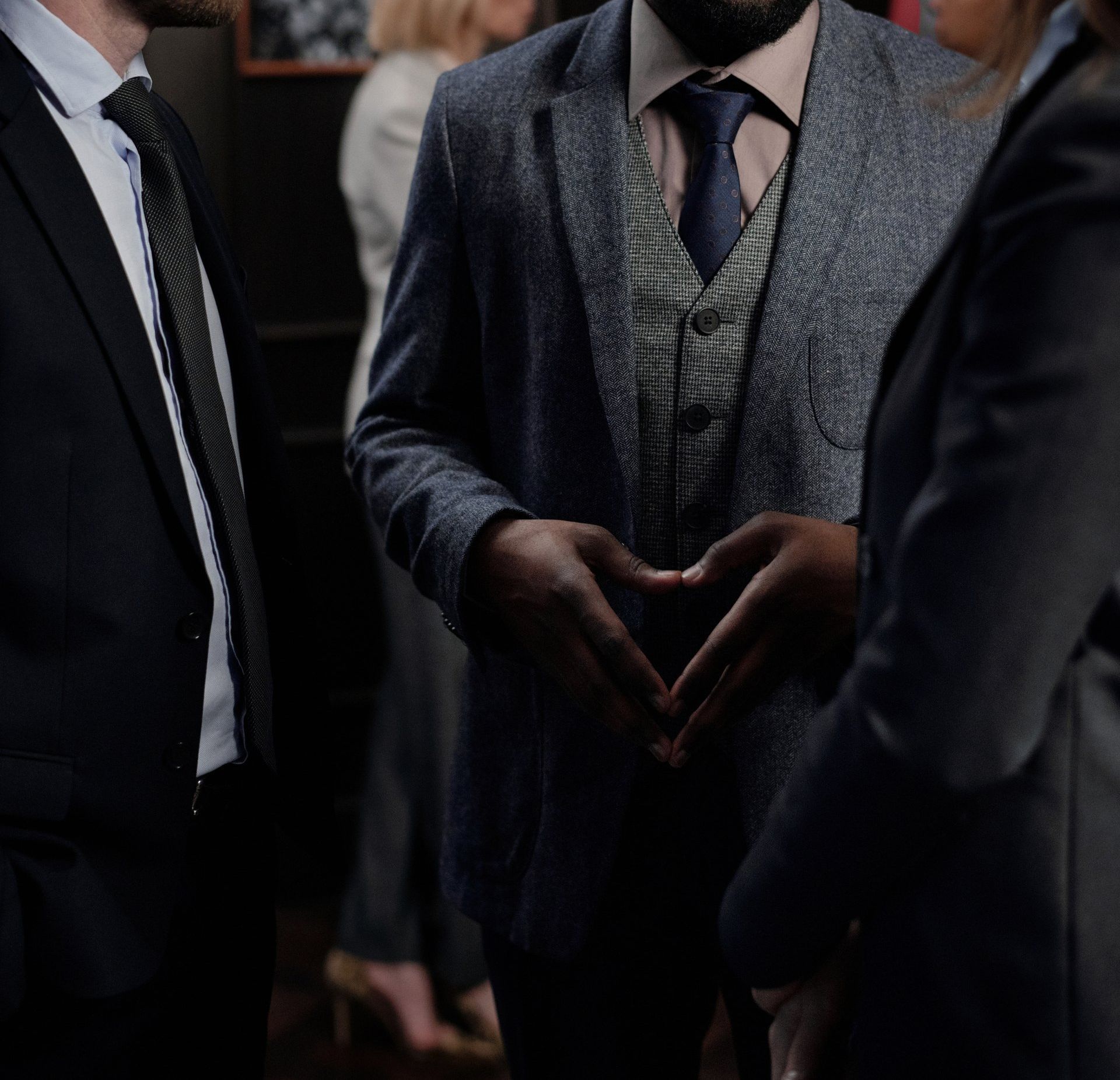 A man in a suit and tie is making a heart shape with his hands