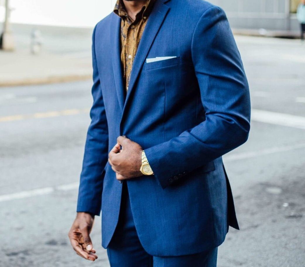 A man in a blue suit is standing on a street